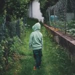 Back of child wearing hoodie looking at lush garden