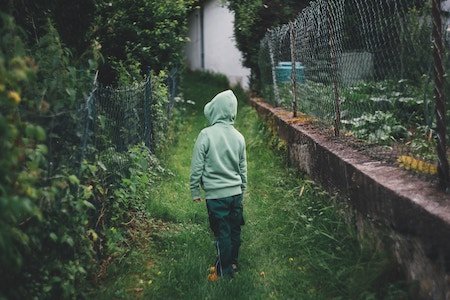 Back of child wearing hoodie looking at lush garden